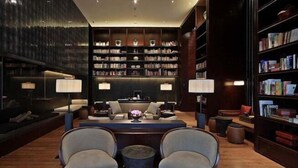 A modern library with a dark wood floor, a central seating area with a table and chairs, and bookshelves on either side. - The Mulian Hotel (Hangzhou Future Science Town Alibaba Xixi Campus) (Hangzhou)