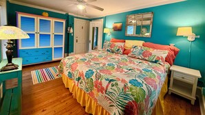 Un dormitorio con una cama, ventilador de techo, armario, mesita de noche y lámpara.