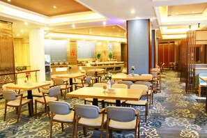 Un comedor de hotel con varias mesas y sillas, alfombra estampada y diseño de interiores moderno.