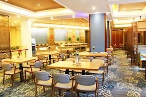 Un comedor de hotel con varias mesas y sillas, alfombra estampada y diseño de interiores moderno.