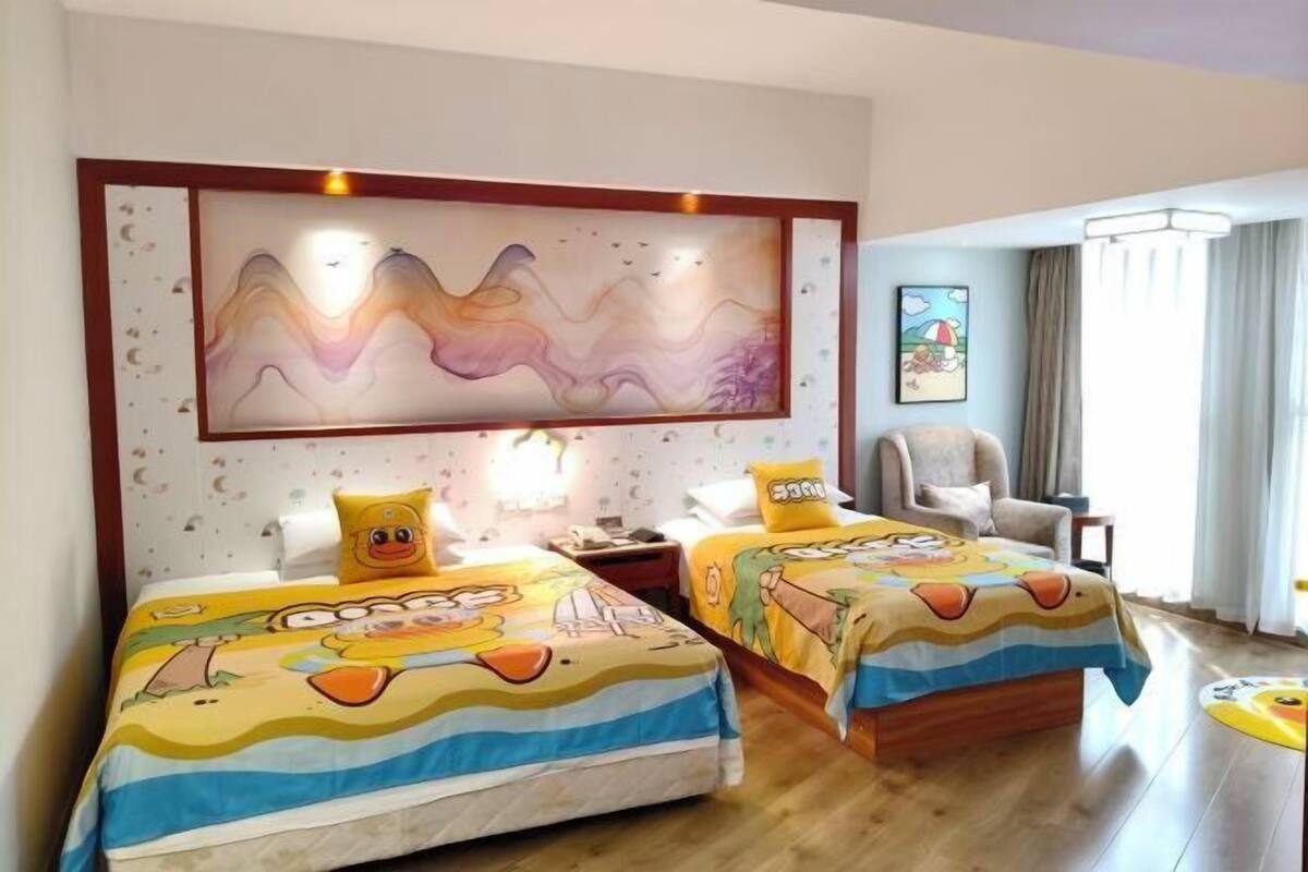 Habitación de hotel con dos camas, un cuadro abstracto grande, una silla y una ventana con cortinas.