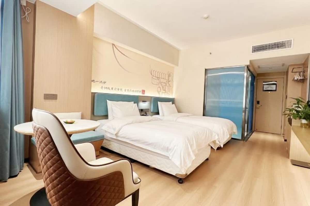 Una habitación de hotel con una cama, una mesita, una silla y un escritorio.