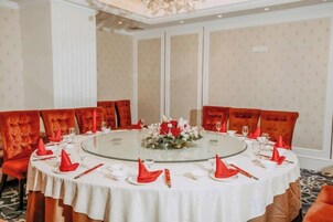 Un salón de conferencias con una mesa redonda, sillas tapizadas en rojo y un mantel blanco.