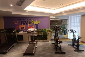 A gym with exercise equipment, a reception desk, and a wall with motivational text. - Jinhua Hotel (Huangshi)