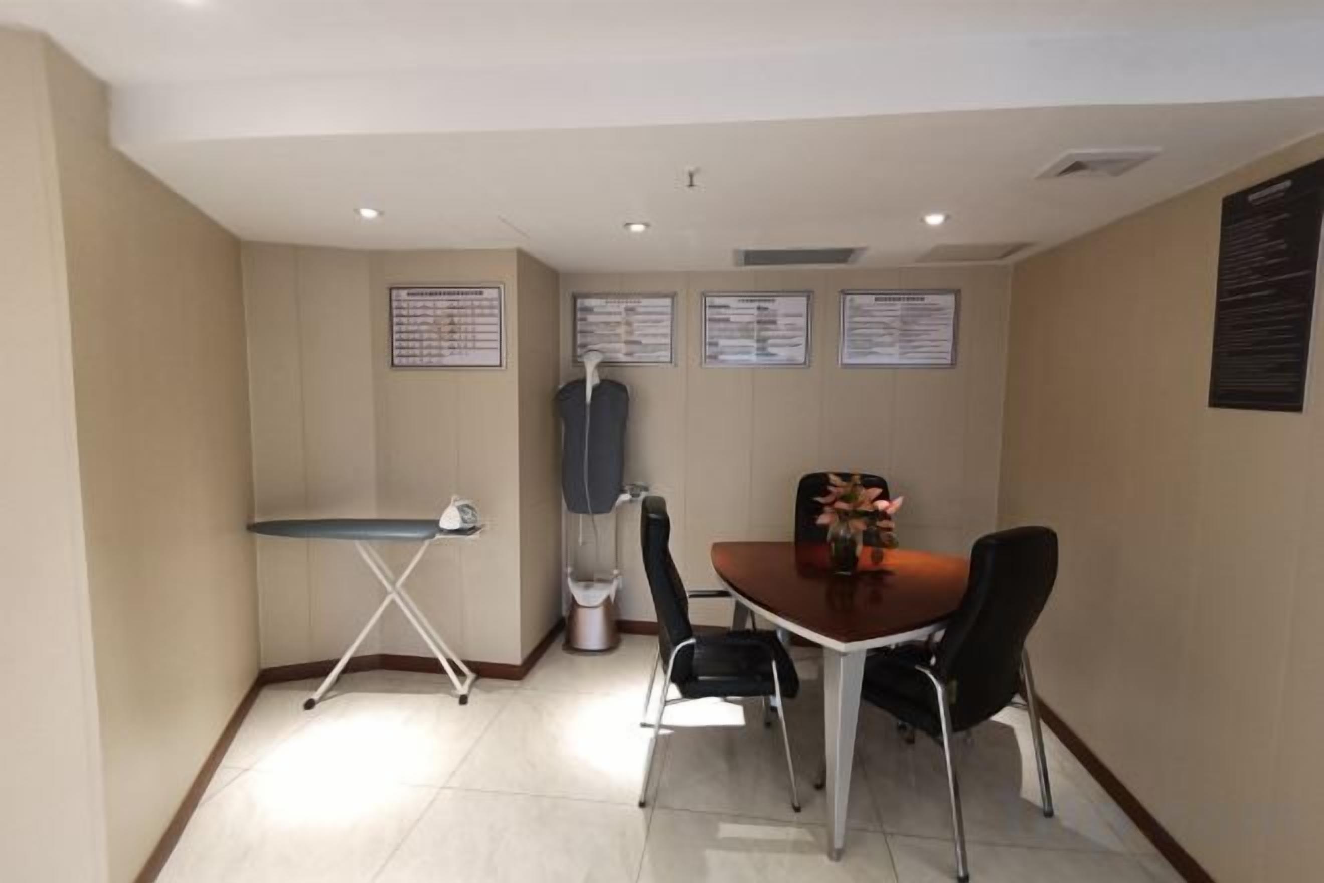 Une salle de conférence équipée d’une table, de chaises, d’une planche à repasser et de panneaux d’affichage fixés au mur.