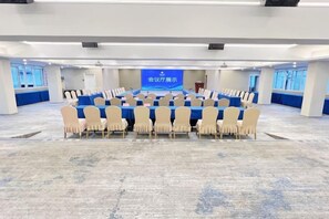 A conference room with a long table and chairs, a projection screen, and a blue carpet. - Jinhua Hotel (Huangshi)