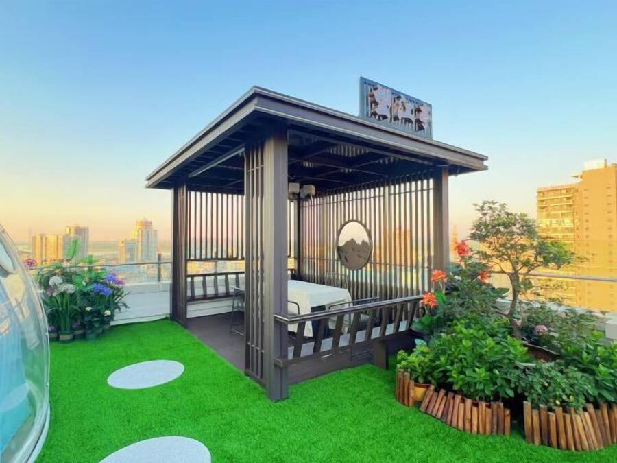 Ein Dachgarten mit einem hölzernen Pavillon, synthetischem Rasen und Blick auf die Stadtlandschaft.