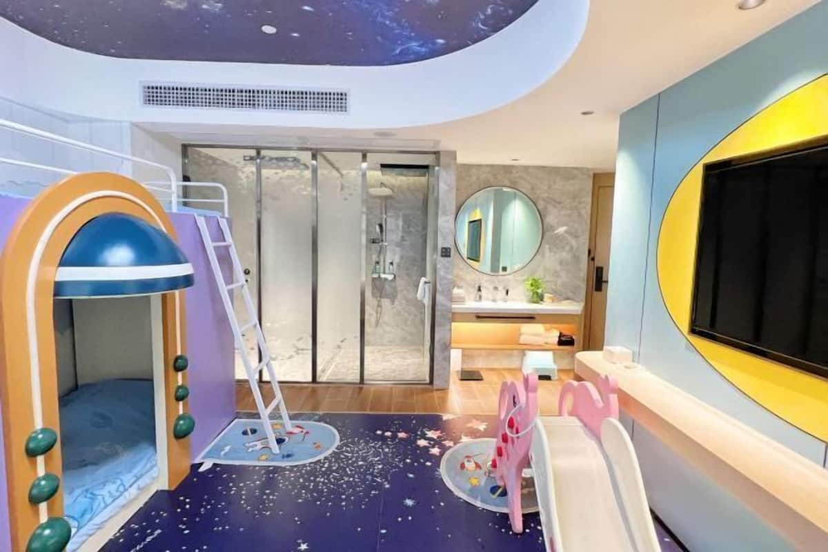 Zona de juegos infantiles con tobogán, pared de escalar y un espejo circular.