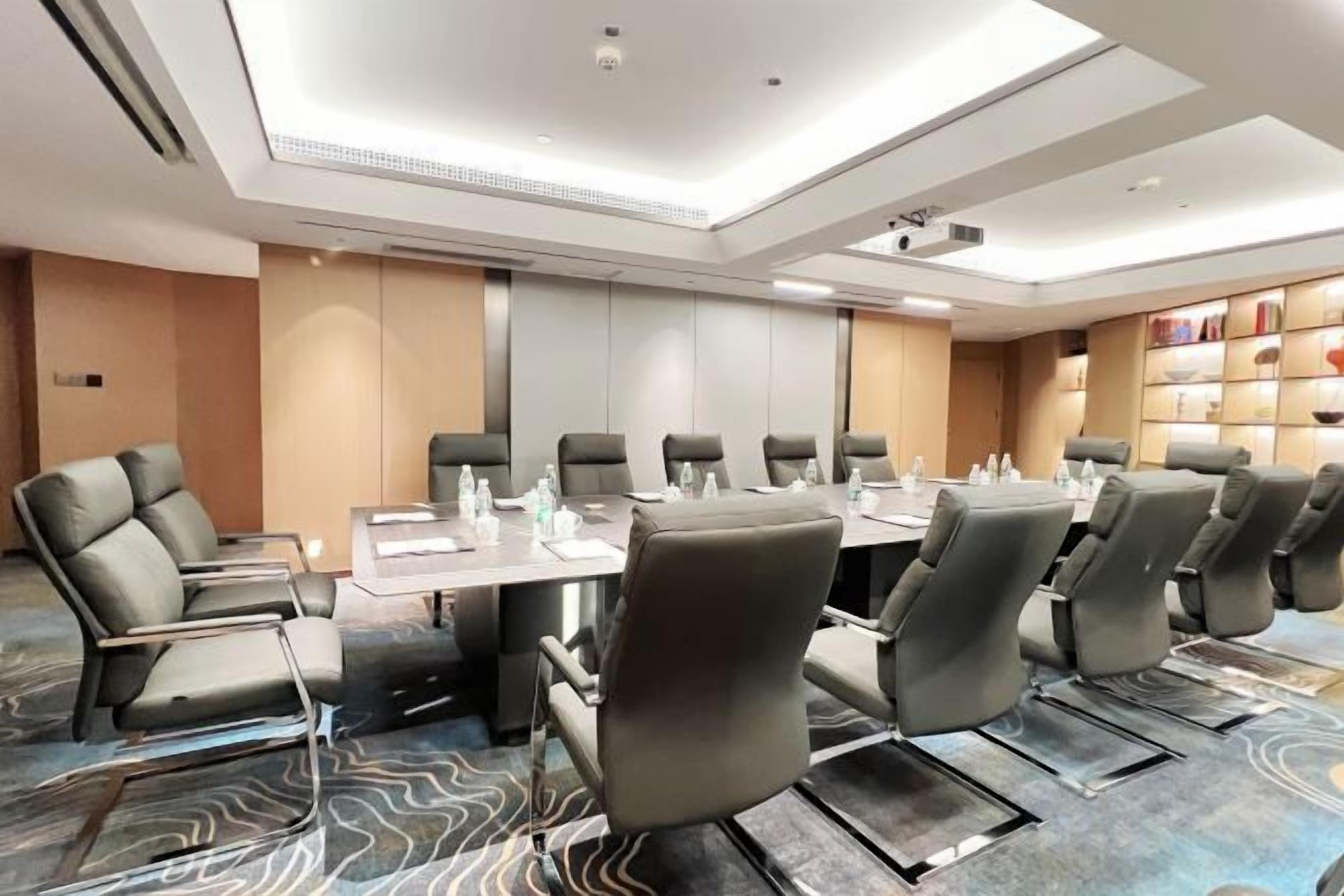 A conference room with a long table, multiple chairs, and a projector screen.