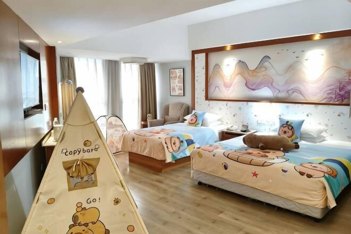 Habitación de hotel con dos camas, televisión, escritorio y una silla.