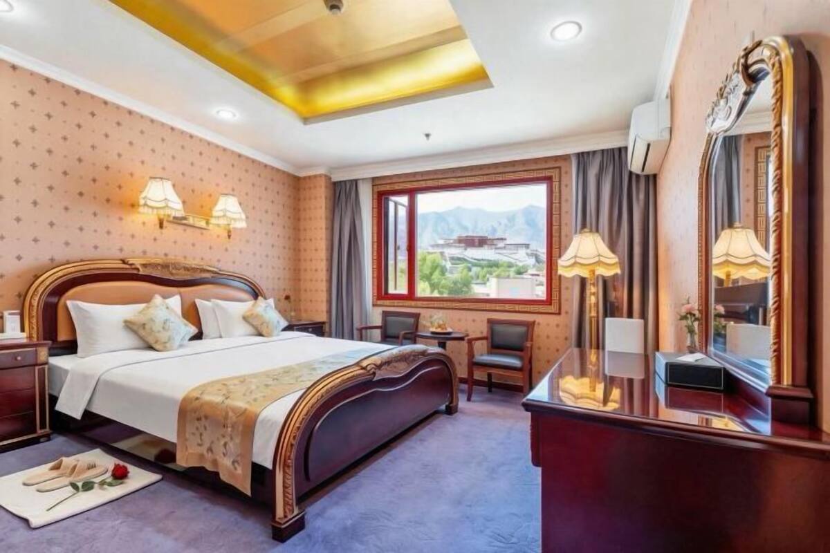 A hotel room with a large bed, bedside lamps, a desk, and a view of the mountains.