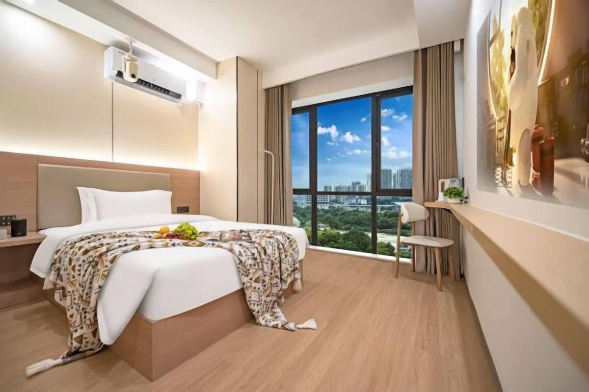 Una habitación de hotel moderna con una cama grande, un escritorio y vistas a la ciudad.