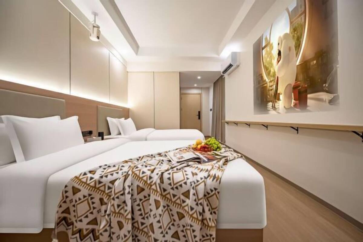 Una habitación de hotel moderna con dos camas, un ventanal grande y un cuadro en la pared.