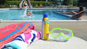 Zona junto a la piscina con una toalla, una botella y gafas.