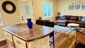 Una cocina moderna con una isla central, un rincón de comedor con sofá y un ventanal que aporta luz natural.
