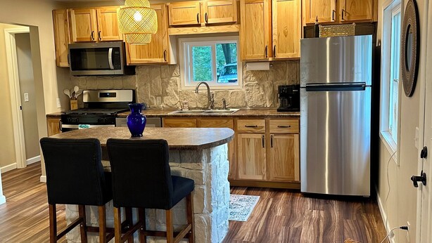 Una cocina moderna con armarios de madera, un refrigerador de acero inoxidable y una pared decorativa de piedra.