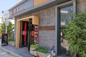 A hotel entrance with a modern facade, a wooden door, and a signboard. - Pushi (Shenzhen)