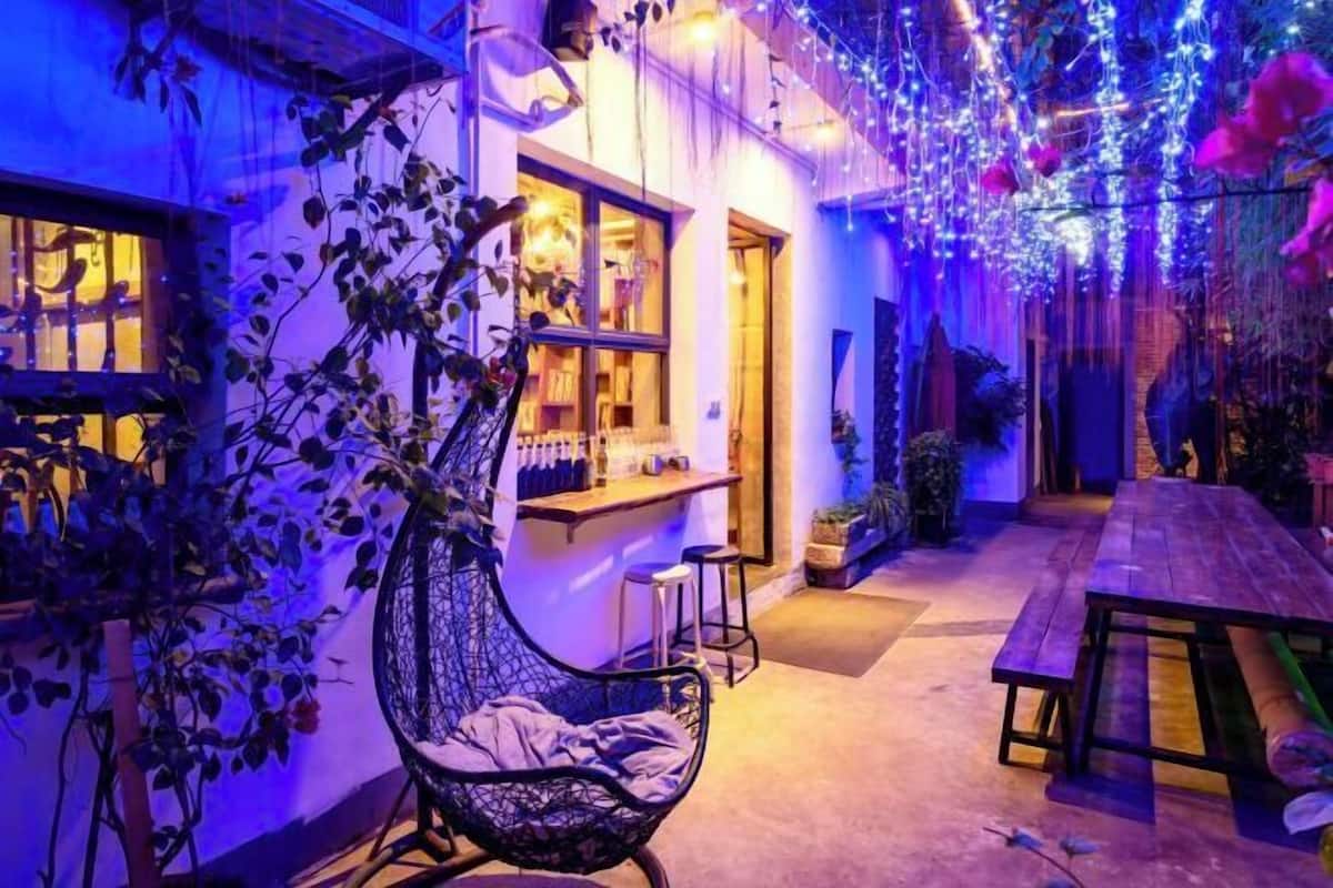 A cozy outdoor seating area with a hanging chair, a wooden table, and a bar counter.