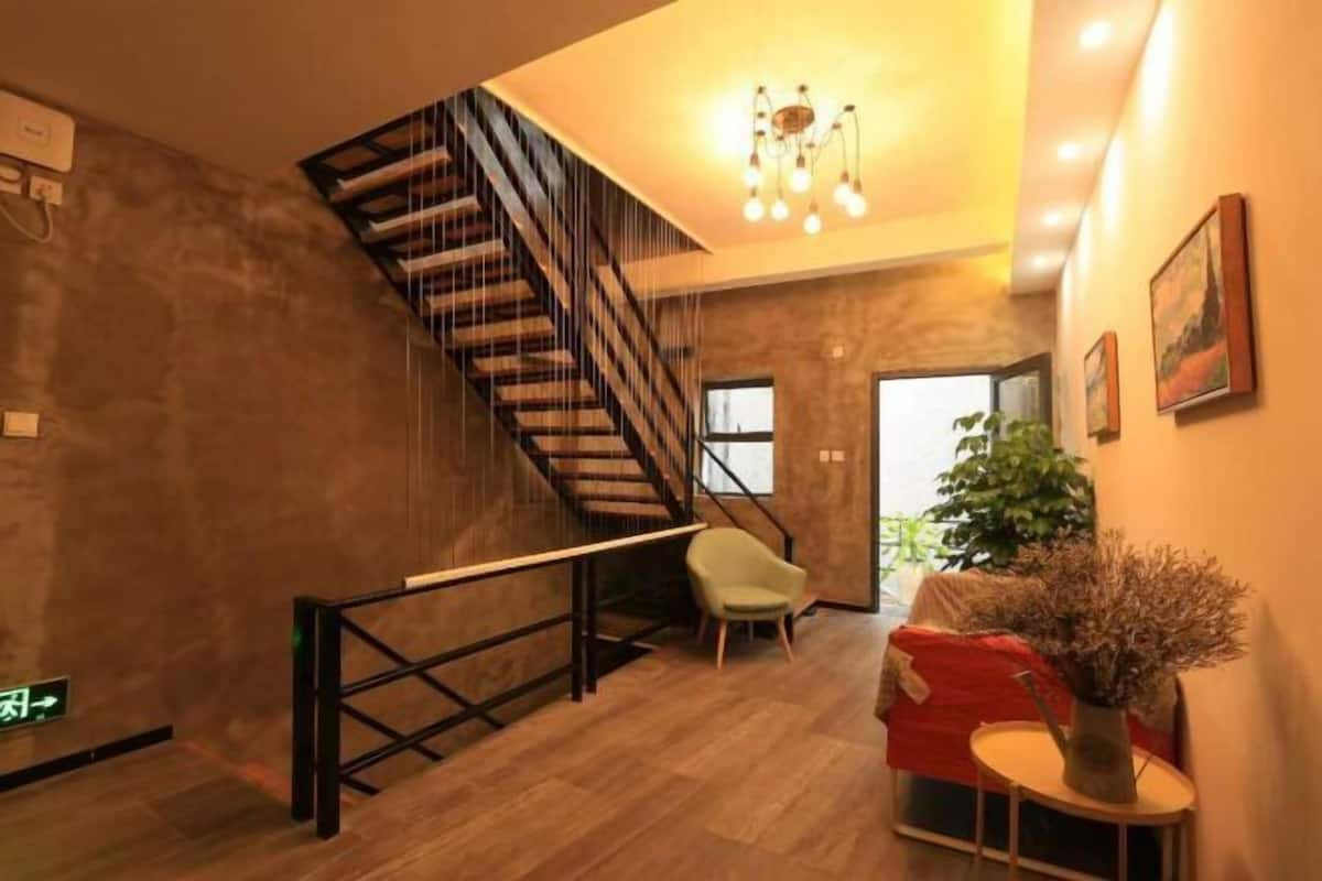 A modern interior with a wooden staircase, a sofa, a small table with a vase, and a plant.