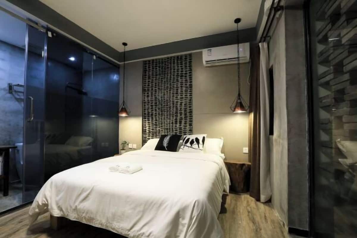 A modern bedroom with a bed, bedside tables, a wall-mounted air conditioner, and a patterned wall.