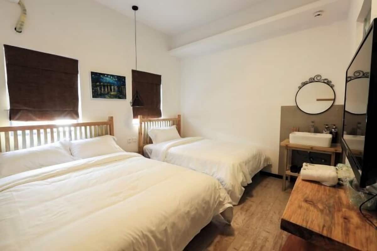 A bedroom with two beds, a wooden headboard, a bedside table with a mirror, and a nightstand.