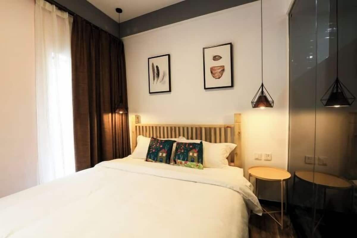 A hotel room with a large bed, two bedside tables, a wooden headboard, and artwork on the walls.