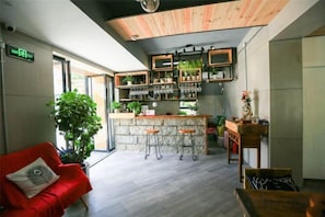 A modern interior with a bar area, seating, and a large plant. - Pushi (Shenzhen)