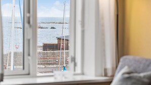 Udsigt fra et vindue over et kystlandskab med en trækonstruktion og en redningskrans.