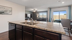 Una cocina moderna con encimeras de granito, armarios oscuros y lavavajillas integrado.