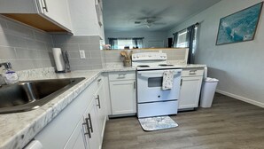 A modern kitchen with white cabinetry, a stainless steel sink, a double oven, and a wooden floor. - It's beach time! Enjoy the sunshine! (Ormond Beach)