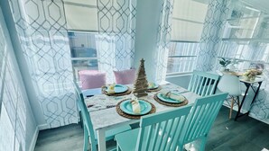 A dining area with a table set for four, surrounded by teal chairs, and a decorative tree centerpiece. - It's beach time! Enjoy the sunshine! (Ormond Beach)