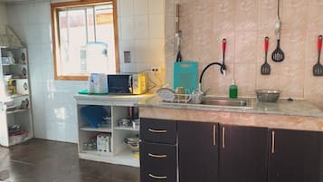 Een koelkast, een microgolfoven, een oven, kookgerei, borden en bestek