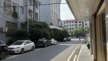 A street view with parked cars, buildings, and a clear sky.