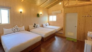 Una baita in legno con due letti, una finestra, una porta e un soffitto con travi a vista.