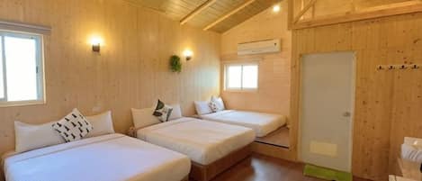 A wooden-paneled room with two beds, a window, and a door.
