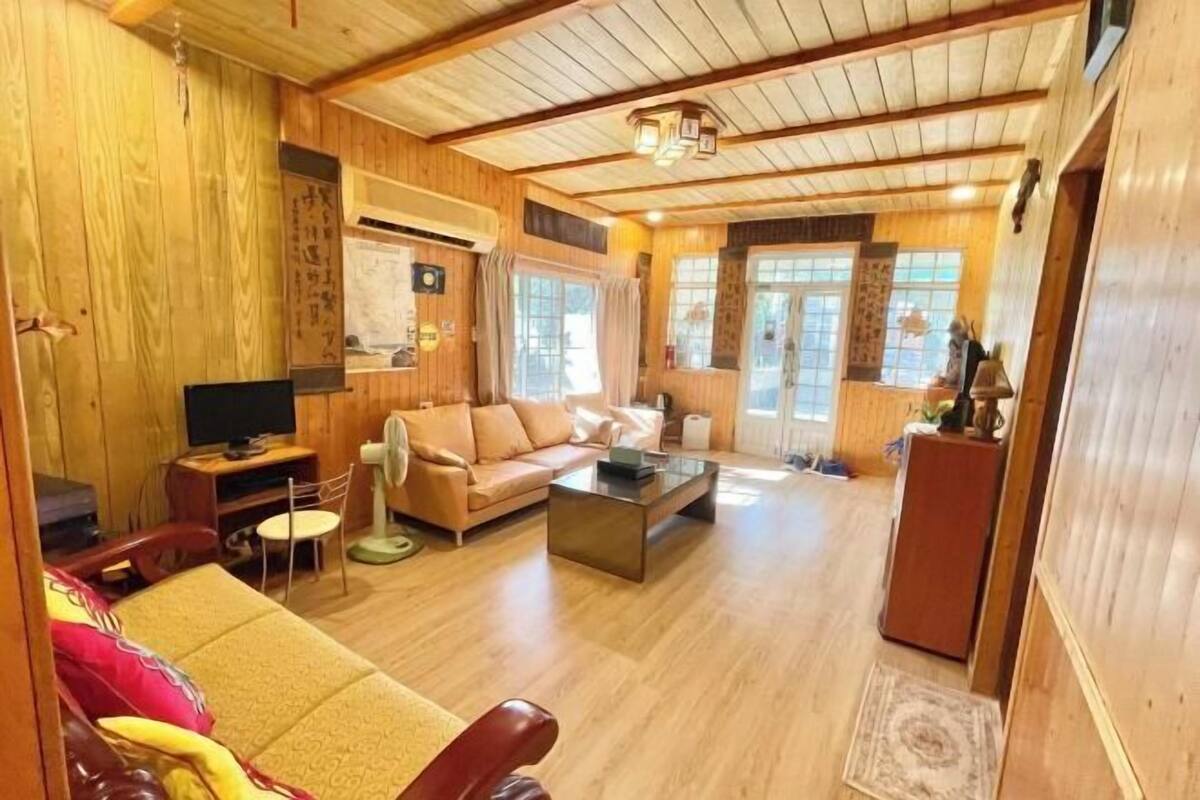 A wooden interior with a sofa, a coffee table, and a television.