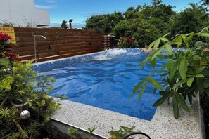 A swimming pool with clear water, surrounded by a wooden fence and greenery. - Quiet Home Hall (Pingtung)