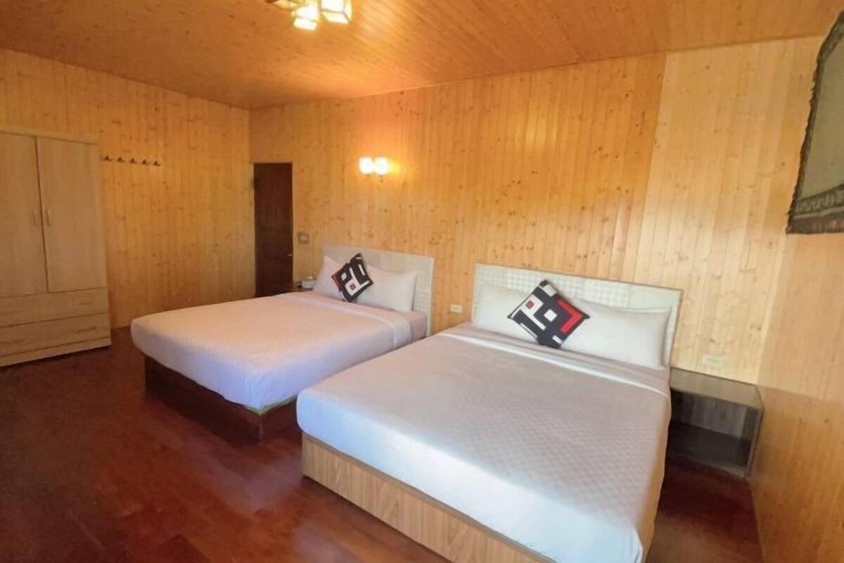 A room with two beds, wooden walls, and a wardrobe.
