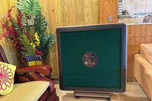 A green pool table with a logo in the center, a wooden chair with a cushion, and a vase with flowers. - Quiet Home Hall (Pingtung)