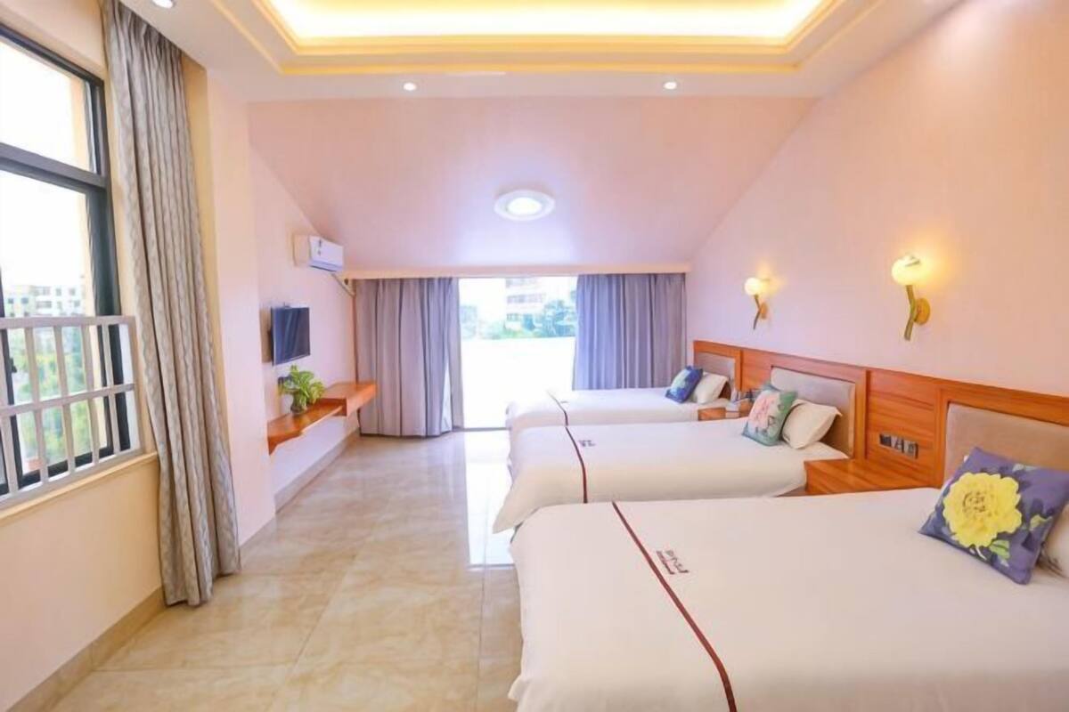Een hotelkamer met twee bedden, een televisie, een raam met gordijnen en een plafondlamp.