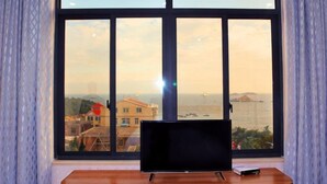 A room with a large window, a wooden table, and a black object on the table. - Weizhou Island Rainbow Hotel (Putian)