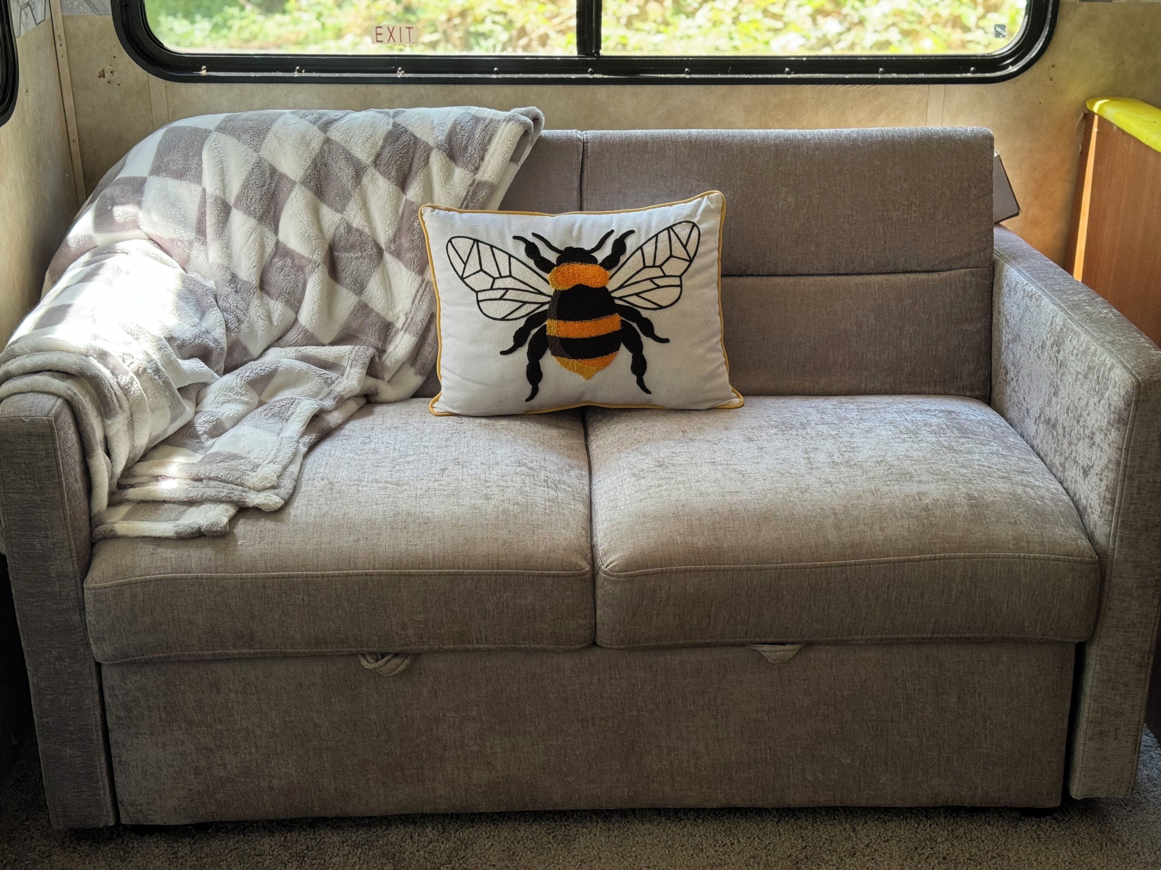 Un sofá con un cojín de abeja y una manta cuadriculada.