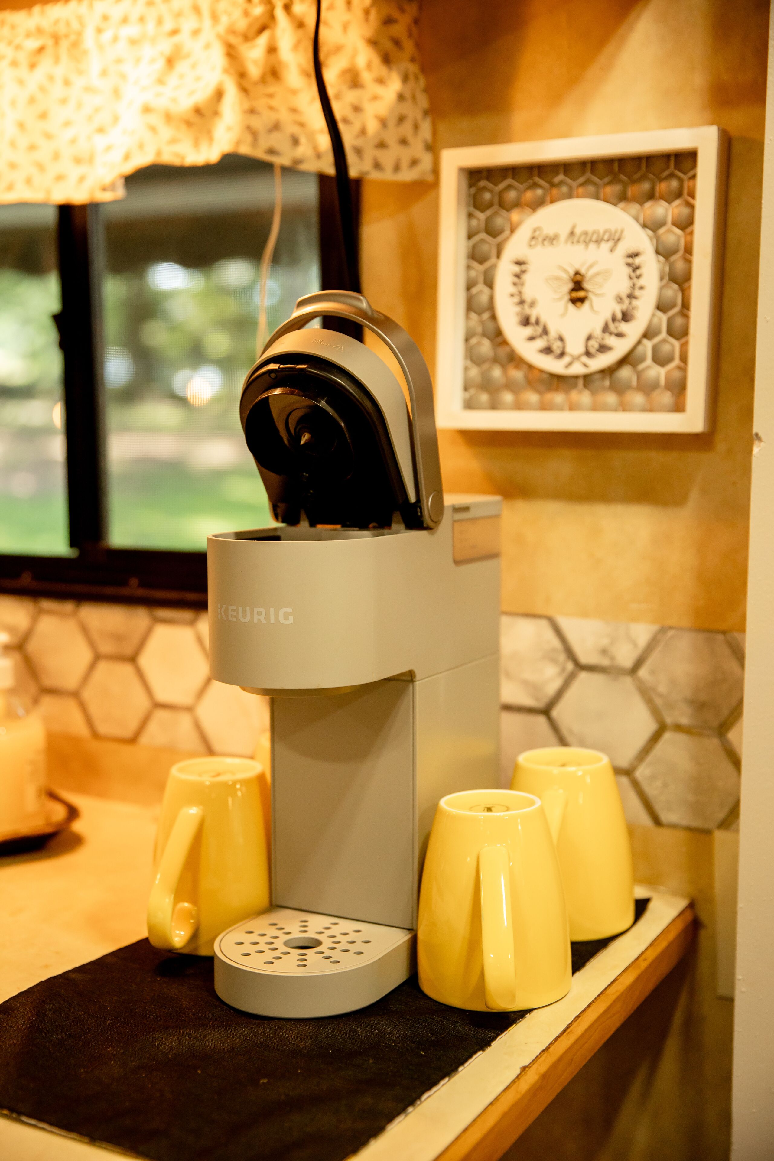 Une machine à café Keurig avec quatre tasses jaunes posées sur un tapis noir.