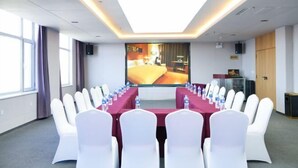 A conference room with a long table, white chairs, and a large screen displaying a hotel room. - Henghui Hyatt Hotel (Shijiazhuang)