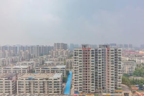 A high-rise residential building with multiple balconies and a blue water feature in the foreground.