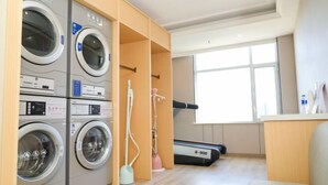 A laundry room with multiple washing machines, a treadmill, and a window providing natural light. - Henghui Hyatt Hotel (Shijiazhuang)