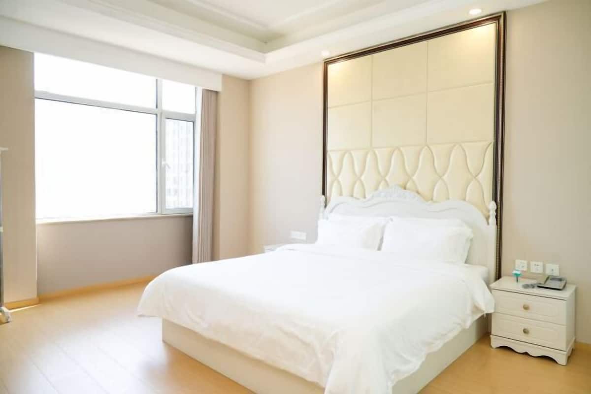Une chambre à coucher avec un grand lit, une table de chevet et une fenêtre.