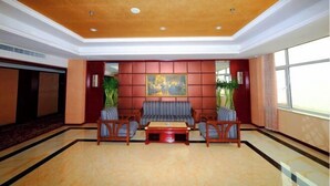 A lobby with a sofa set, chairs, a coffee table, and a painting on the wall. - Henghui Hyatt Hotel (Shijiazhuang)
