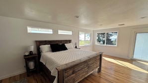 A bedroom with a wooden bed, white walls, and large windows. - Lakefront Ranch with Hot Tub and WiFi in Crescent City (Crescent City)