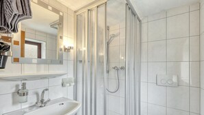 A modern bathroom with a glass-enclosed shower, a sink with a mirror above it, and a toilet. - Lovely apartment in Bischofsheim with WiFi (Bischofsheim)